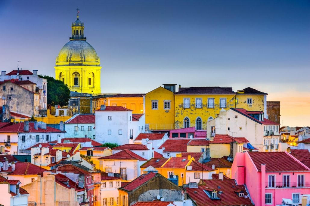 A picture of a yellow church steeple and other colourful houses and rooftops in the Alfama area of Lisbon