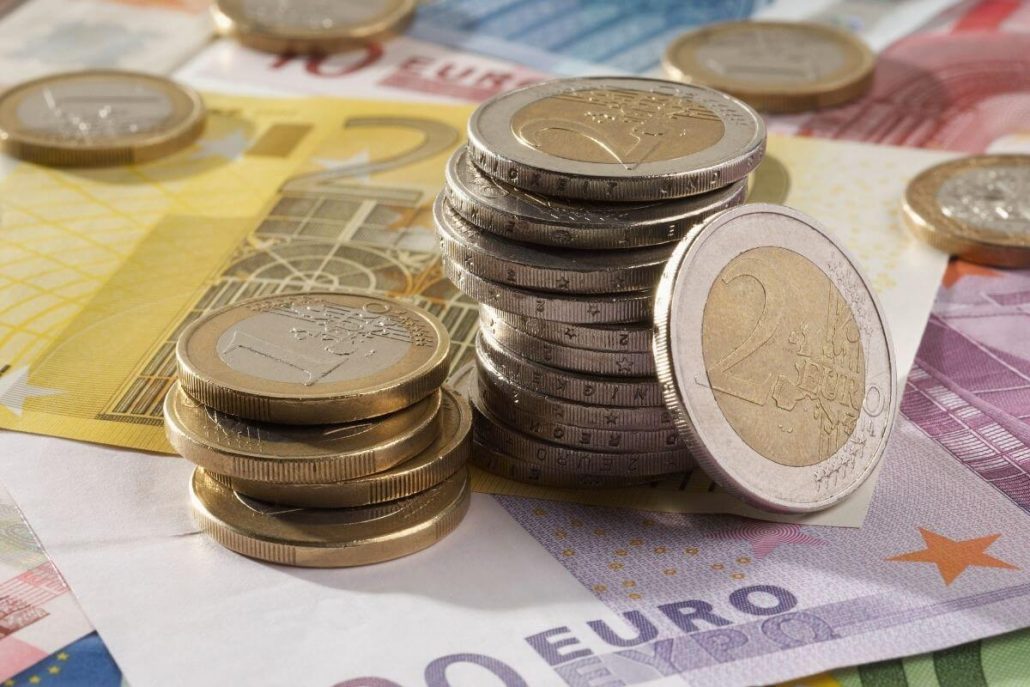 A picture of some one and two euro coins piled on top of some larger euro notes